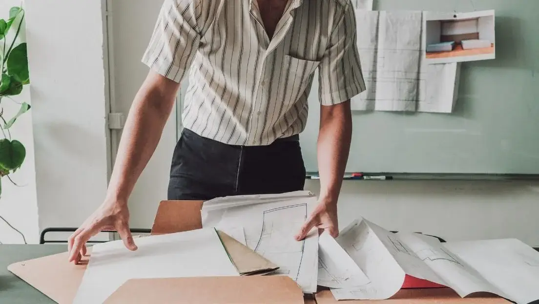 STanding Man looking at architect papers on a table